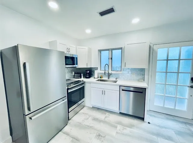 a kitchen with stainless steel appliances granite countertop a refrigerator sink and stove
