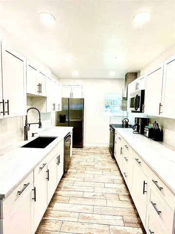 a large kitchen with kitchen island granite countertop a sink and white cabinets