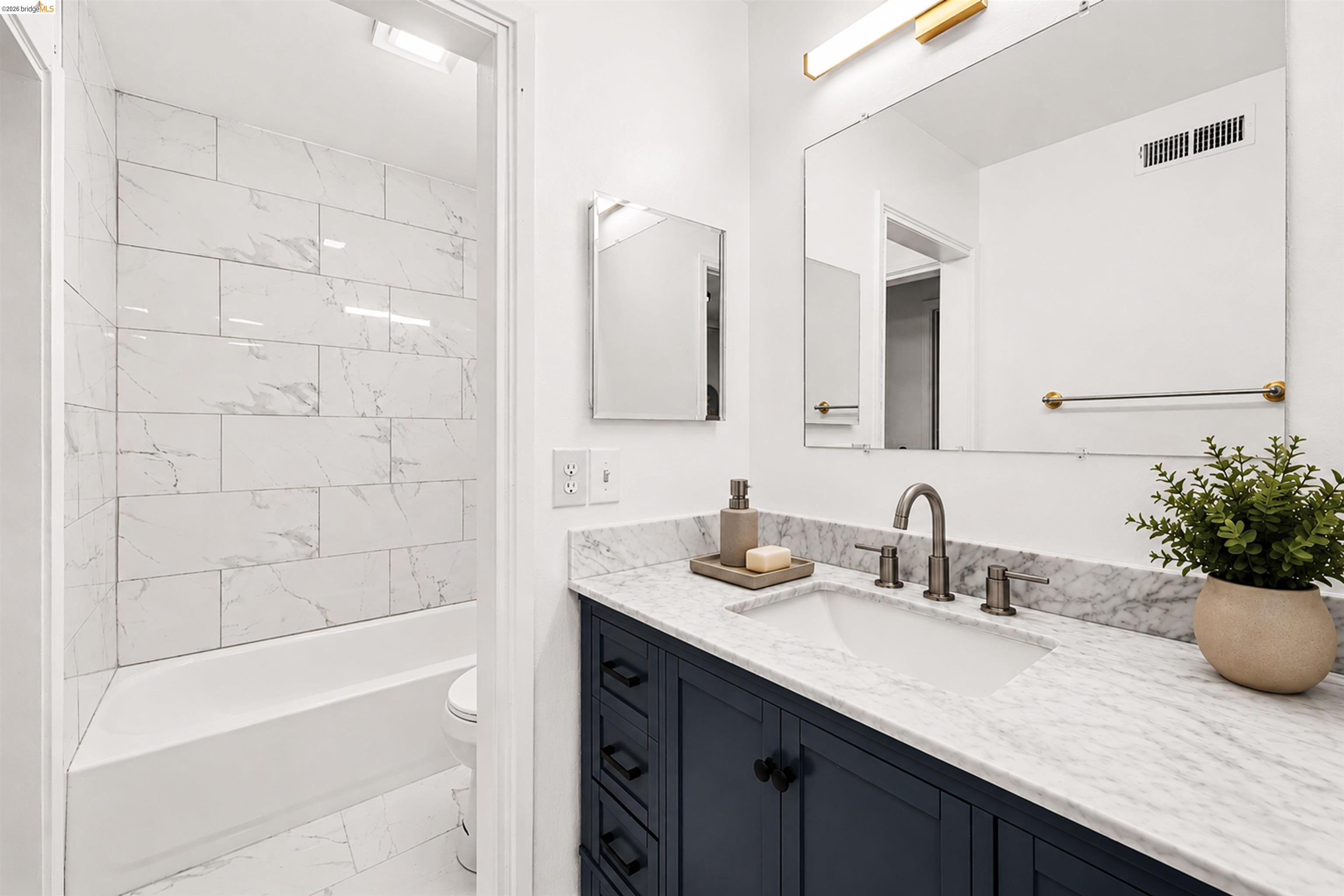 4186 San Pablo Dam Road, Unit A El Sobrante, CA 94803 - Photo 16 of 34 Bathroom featuring a dark blue vanity with black hardware, a white undermount sink, and a white marble-patterned countertop