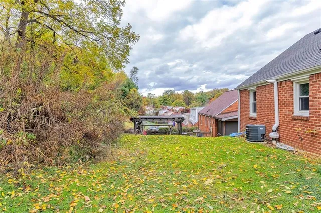 a view of a house with a big yard and large tree