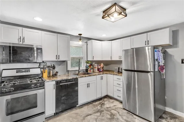 a kitchen with stainless steel appliances a refrigerator a stove a sink cabinets and a refrigerator