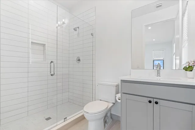 a bathroom with a shower sink vanity mirror and toilet