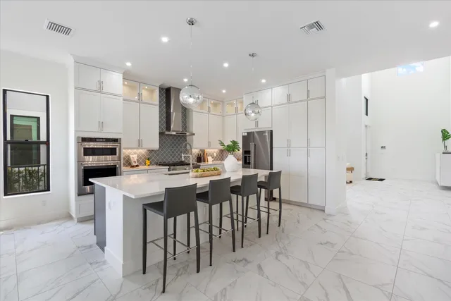 a kitchen with stainless steel appliances kitchen island granite countertop a sink and a refrigerator
