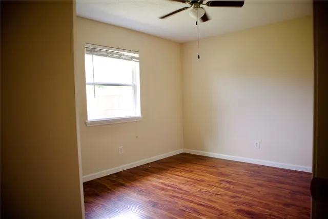 an empty room with a window and a ceiling fan