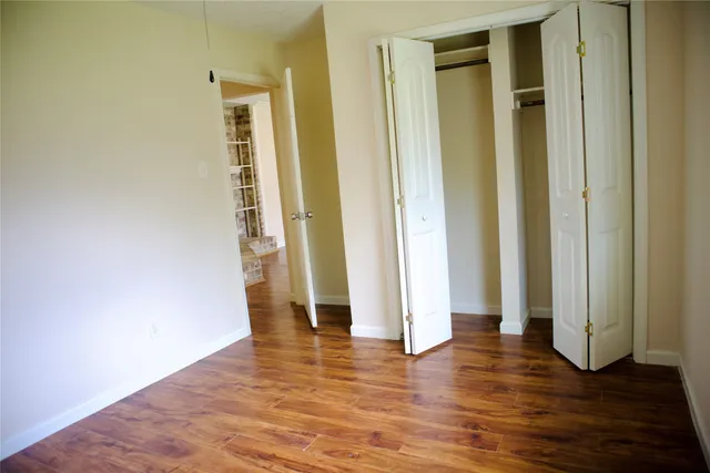 an empty room with wooden floor and entrance