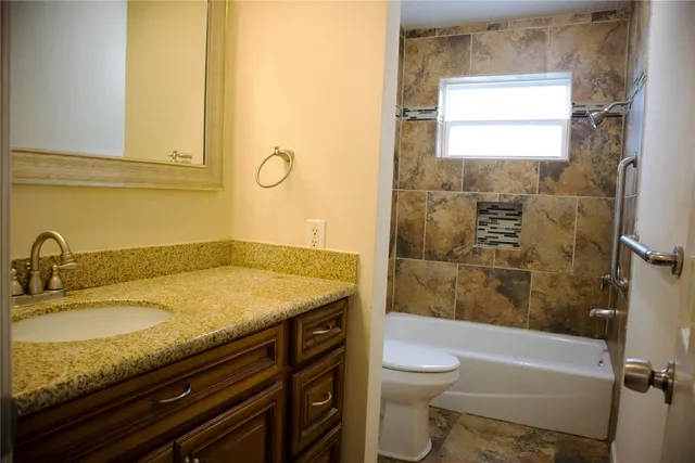a bathroom with a granite countertop sink toilet and shower