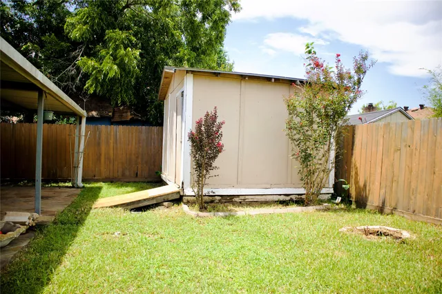 a view of a backyard with table and chairs potted plants and large tree