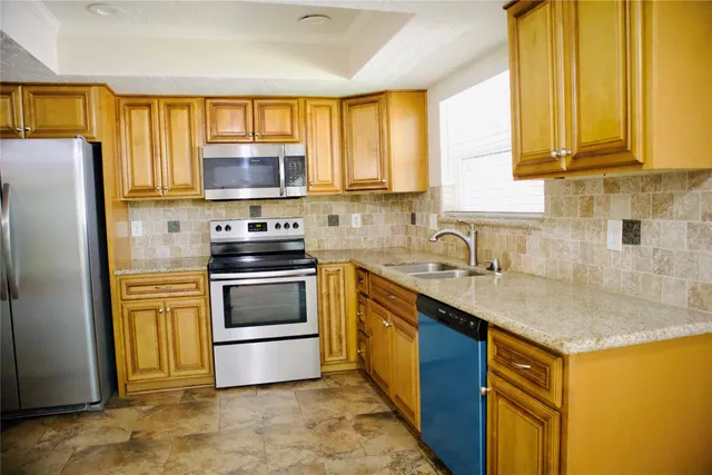 a kitchen with stainless steel appliances granite countertop a stove a sink a refrigerator and a microwave
