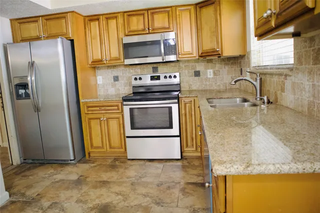 a kitchen with granite countertop a sink a stove and refrigerator