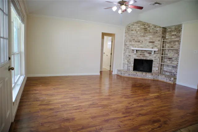 a view of an empty room with wooden floor and a fireplace