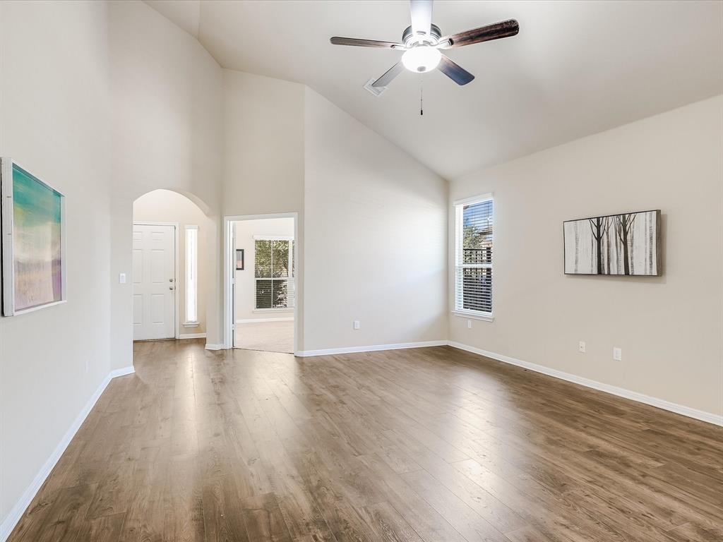 141 Serrano Street Georgetown, TX 78628 - Photo 7 of 19 A well-lit interior features vaulted ceilings and rich hardwood-style flooring, creating an inviting atmosphere.