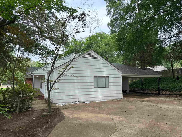 a view of a house with a yard and large tree
