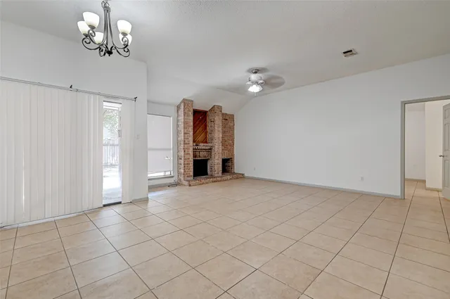 an empty room with chandelier fan and windows