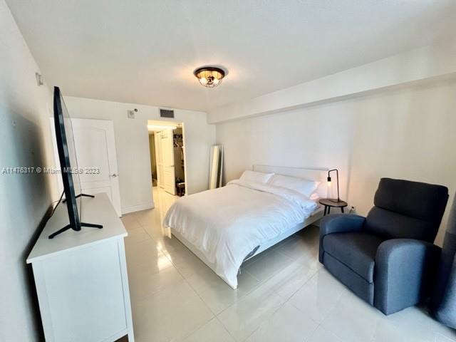 1200 Brickell Bay Drive, Unit 2008 Miami, FL 33131 - Photo 11 of 37 a bedroom with a bed couch and a flat screen tv