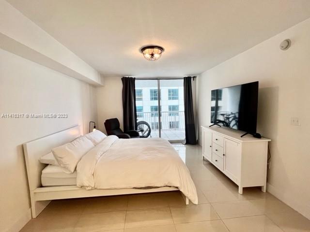 1200 Brickell Bay Drive, Unit 2008 Miami, FL 33131 - Photo 10 of 37 a bedroom with a bed and a flat tv screen on the dresser