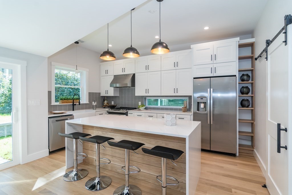 28 Perry Drive Needham, MA 02492 - Photo 8 of 35 a kitchen with granite countertop a refrigerator a stove a dining table and chairs with wooden floor