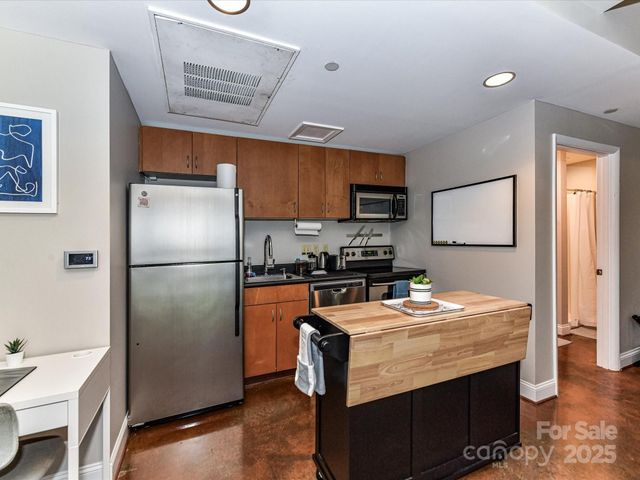 a kitchen with stainless steel appliances kitchen island granite countertop a table chairs sink and cabinets