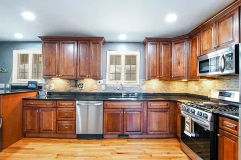 a kitchen with granite countertop wooden cabinets stainless steel appliances and a sink