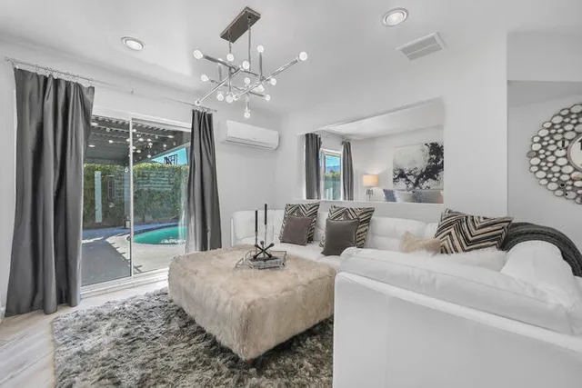 a living room with couch a large window and a chandelier