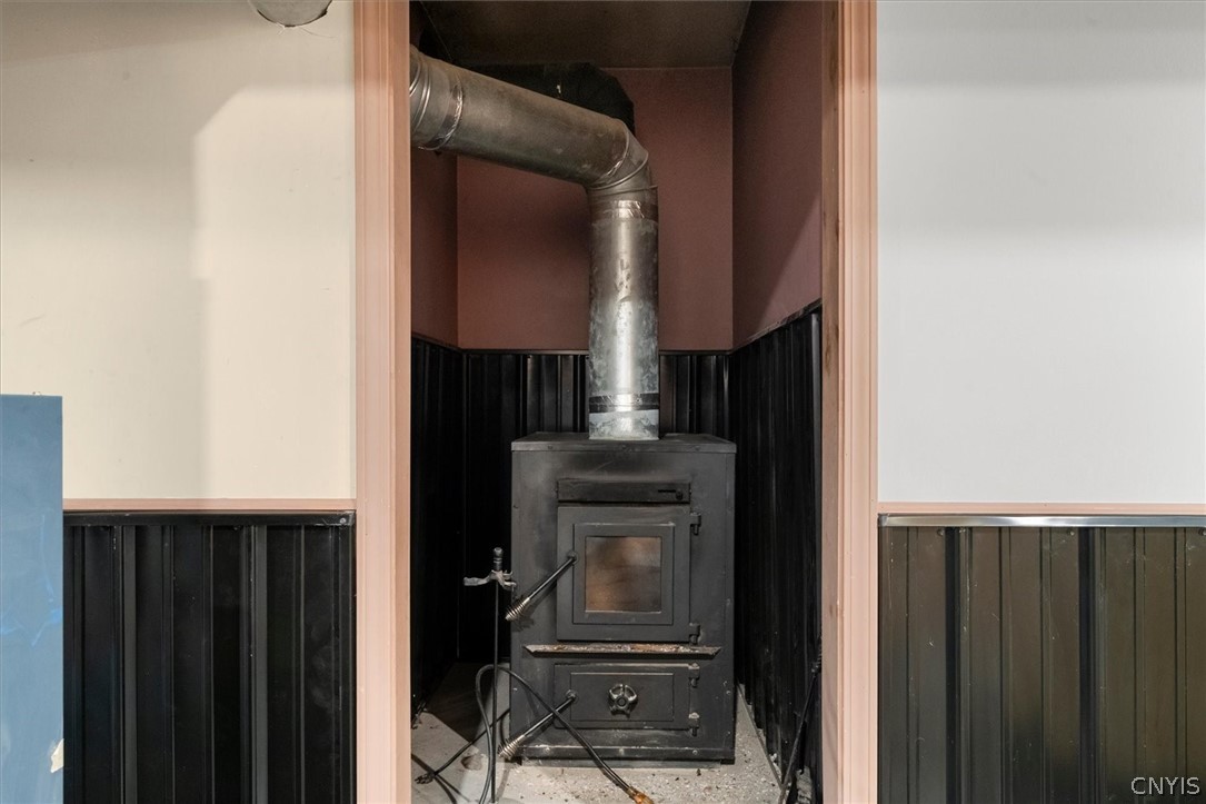 1322 Sawmill Road Sangerfield, NY 13480 - Photo 42 of 50 A classic wood stove sits nestled within a dedicated alcove featuring corrugated wall panels.