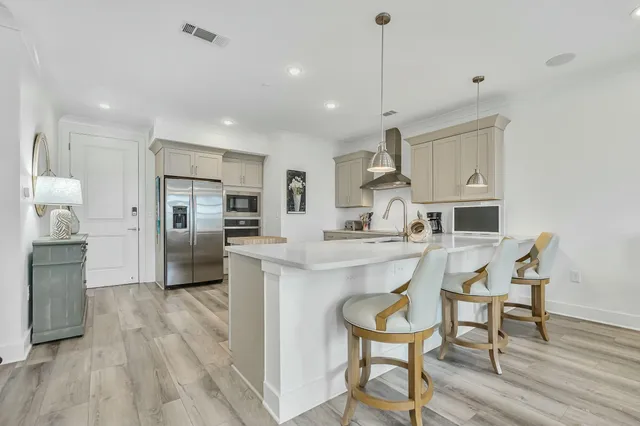 a kitchen with stainless steel appliances kitchen island granite countertop a table chairs refrigerator and microwave