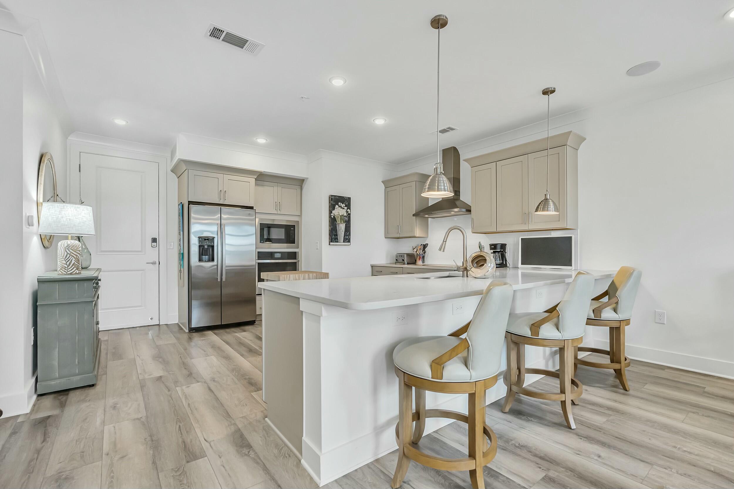 179 South County Highway 393, Unit 445 Santa Rosa Beach, FL 32459 - Photo 6 of 50 a kitchen with stainless steel appliances kitchen island granite countertop a table chairs refrigerator and microwave