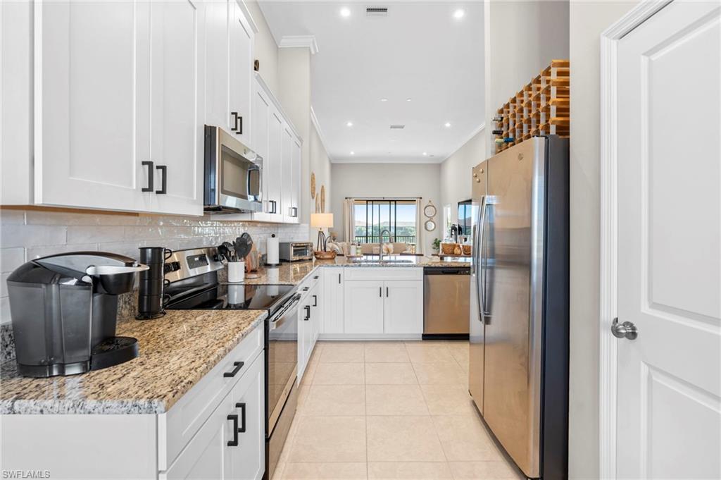 9402 Pocida Court, Unit 202 Naples, FL 34119 - Photo 11 of 31 Kitchen featuring appliances with stainless steel finishes, white cabinets, light stone countertops, light tile patterned floors, and recessed lighting