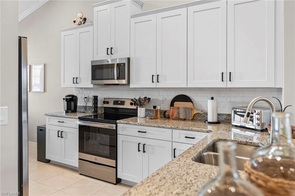 9402 Pocida Court, Unit 202 Naples, FL 34119 - Photo 12 of 31 Kitchen featuring appliances with stainless steel finishes, white cabinets, and backsplash