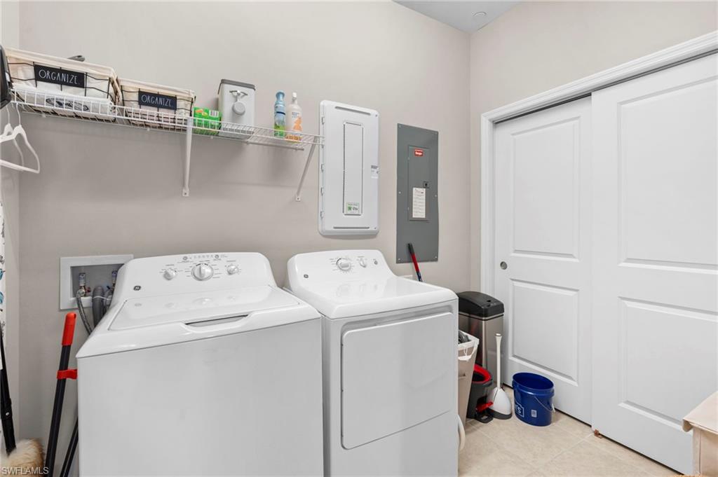 9402 Pocida Court, Unit 202 Naples, FL 34119 - Photo 26 of 31 Washroom with electric panel, light tile patterned floors, and washer and dryer