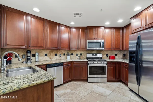 a kitchen with stainless steel appliances granite countertop a stove sink microwave and refrigerator