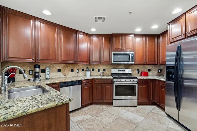 a kitchen with stainless steel appliances granite countertop a stove sink microwave and refrigerator