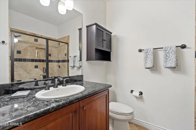 a bathroom with a granite countertop sink toilet and mirror