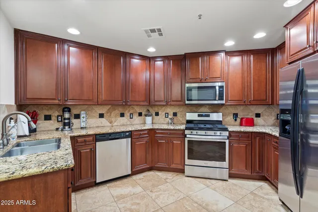 a kitchen with stainless steel appliances granite countertop wooden cabinets a sink and a stove