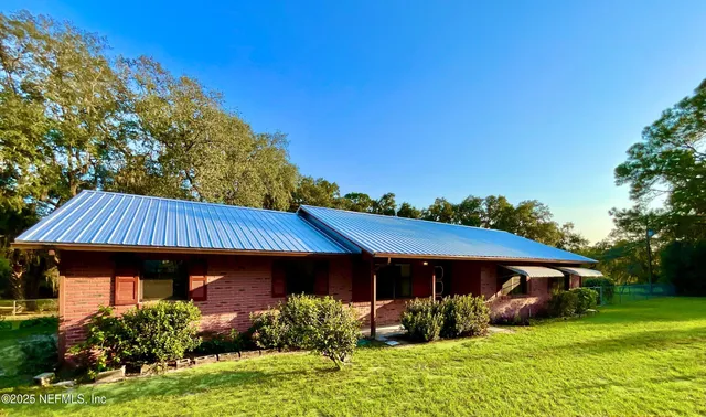 a view of house with garden and tall trees