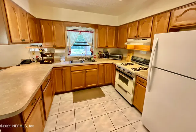a kitchen with stainless steel appliances granite countertop a refrigerator sink stove and white cabinets