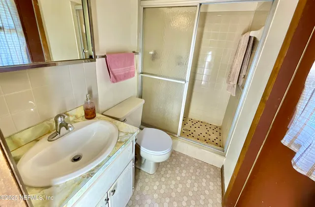 a bathroom with a sink a toilet a mirror and shower