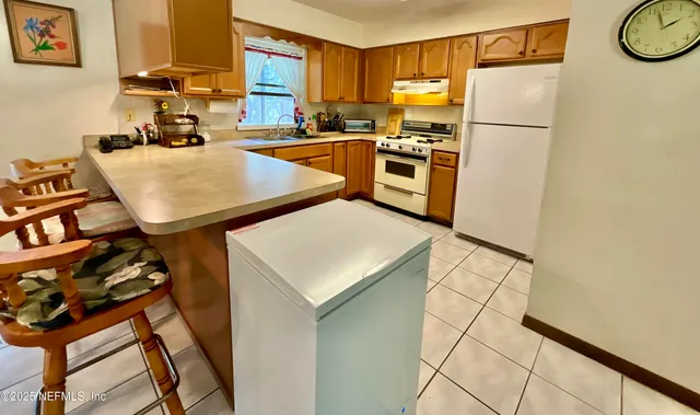 a kitchen with a refrigerator a stove top oven a sink and a window