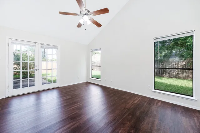a view of an empty room with wooden floor and a window