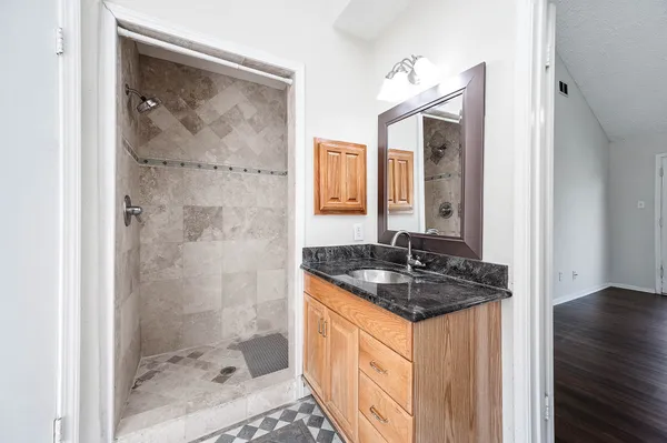 a bathroom with a granite countertop sink a mirror a vanity and shower