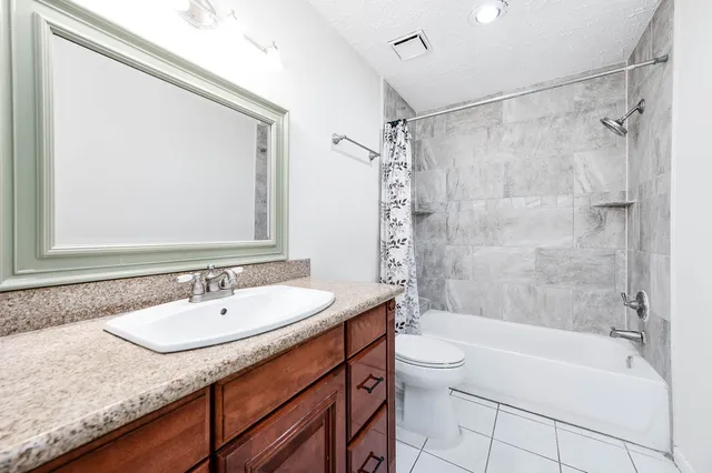 a bathroom with a granite countertop sink a toilet and shower