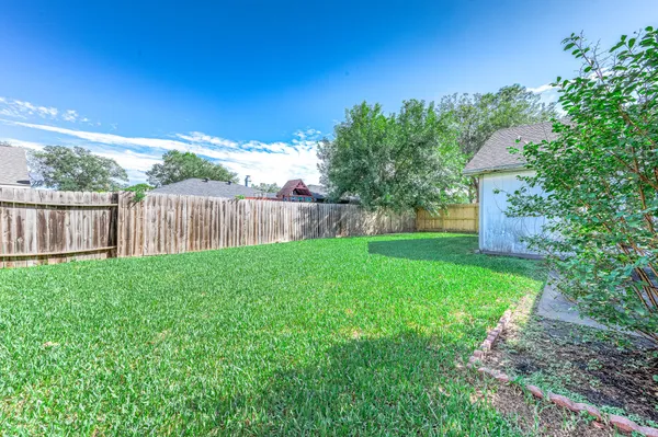 a view of a backyard with large trees and wooden fence