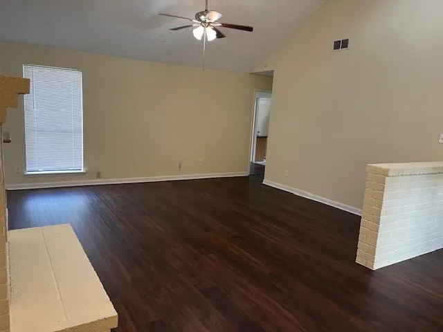 a view of an empty room with wooden floor and a chandelier
