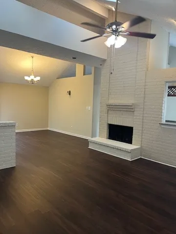 a view of an empty room with wooden floor and a fireplace