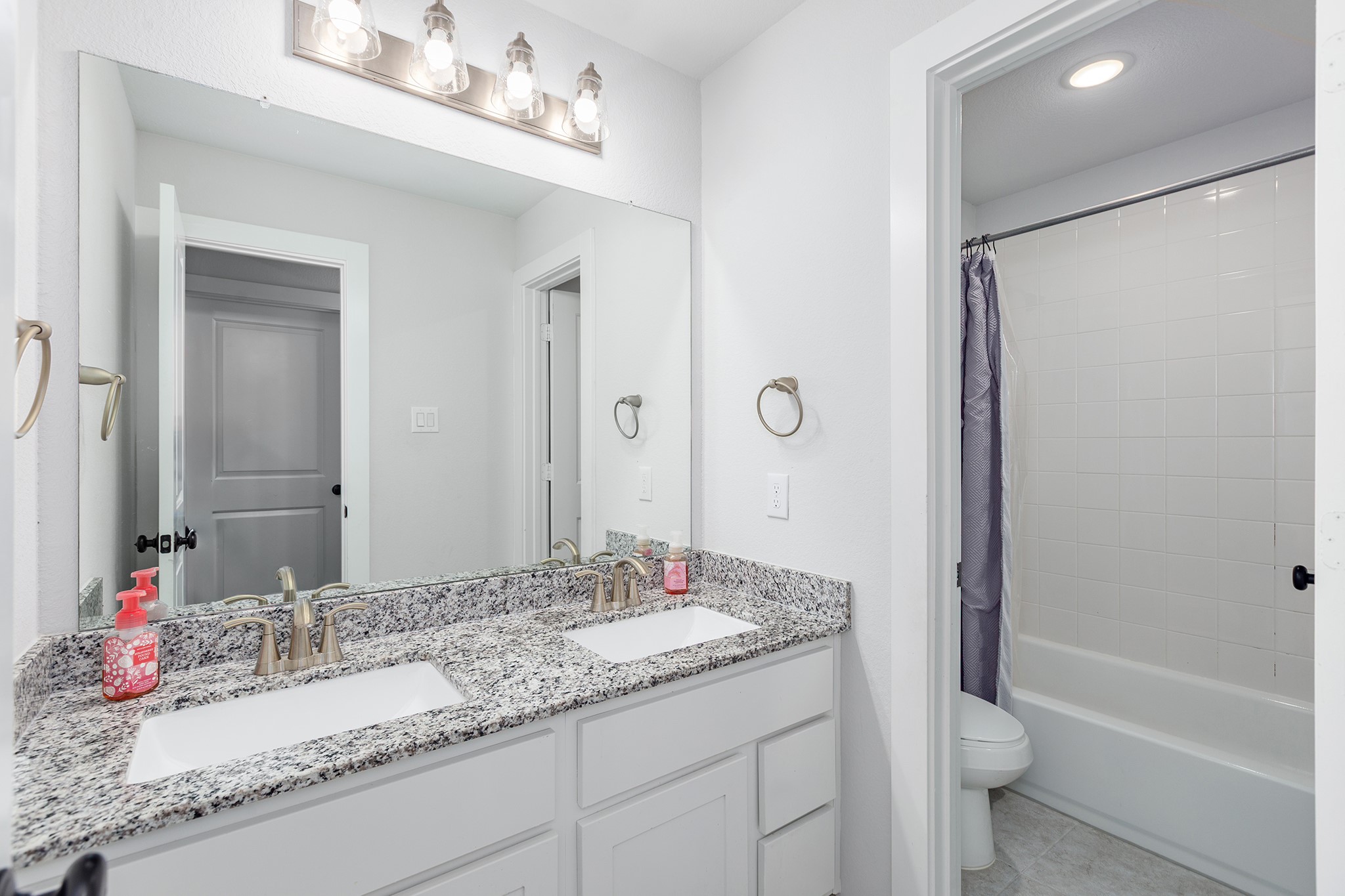 12110 Woodnote Lane Humble, TX 77346 - Photo 28 of 36 a bathroom with a granite countertop sink a mirror and a bathtub