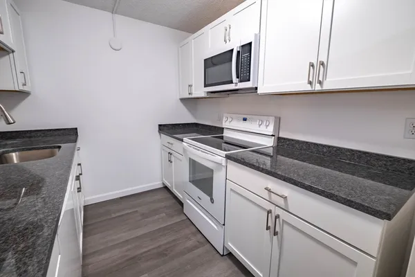 a kitchen with granite countertop cabinets stainless steel appliances and wooden floor