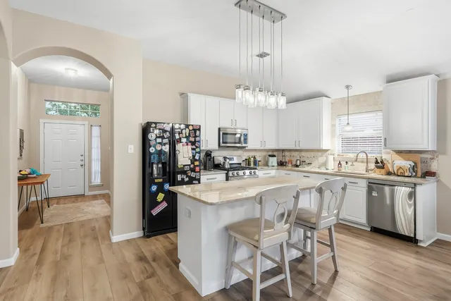a large kitchen with kitchen island a chandelier and stove