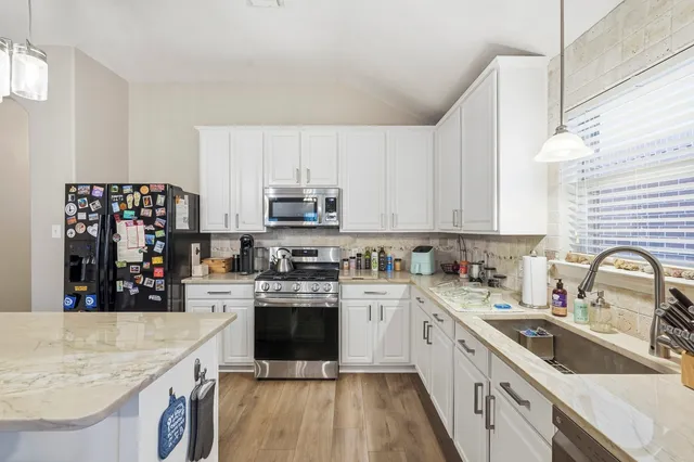 a kitchen with stainless steel appliances granite countertop a sink stove refrigerator and cabinets