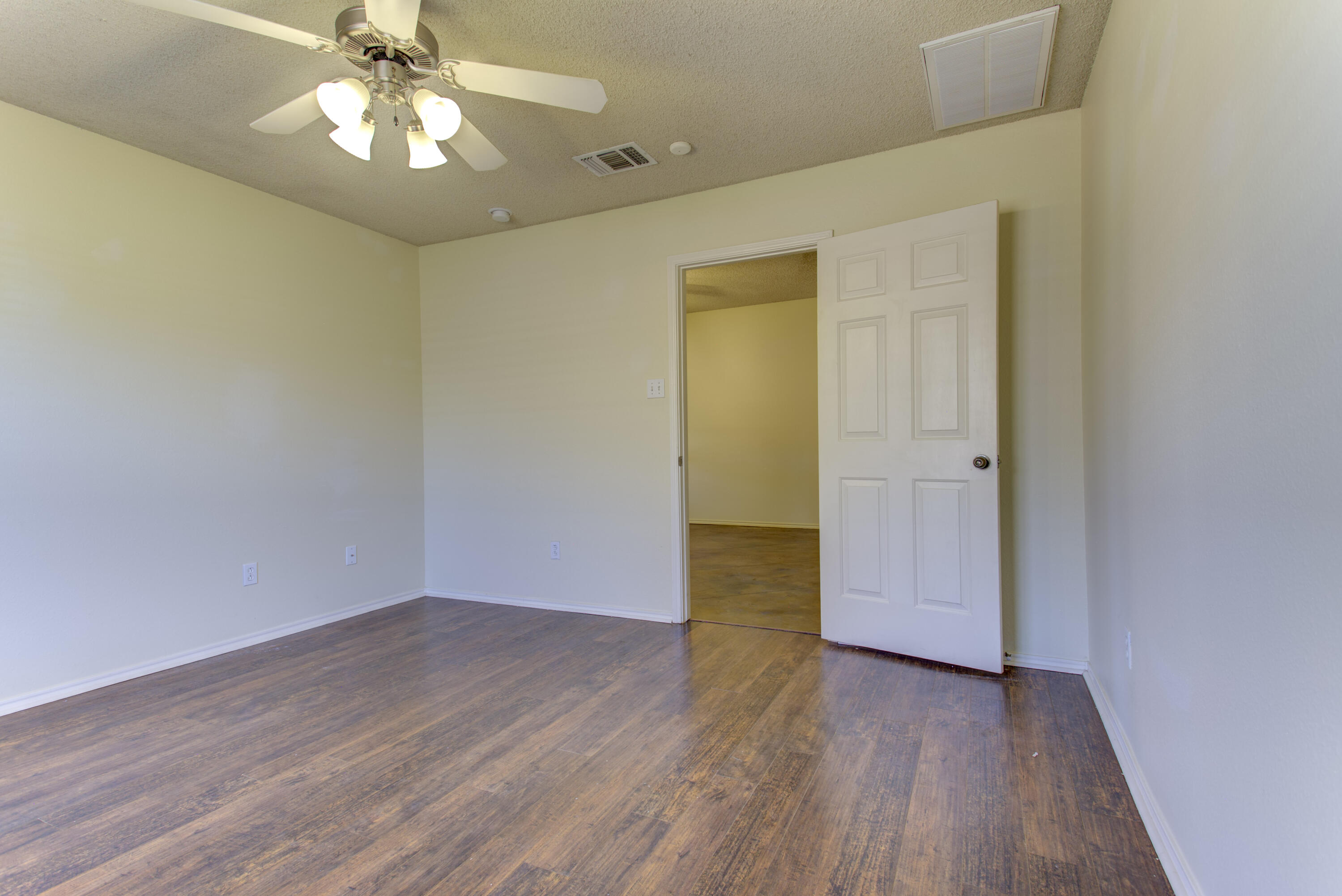 6804 7th Street Lubbock, TX 79416 - Photo 16 of 42 an empty room with wooden floor and ceiling fan