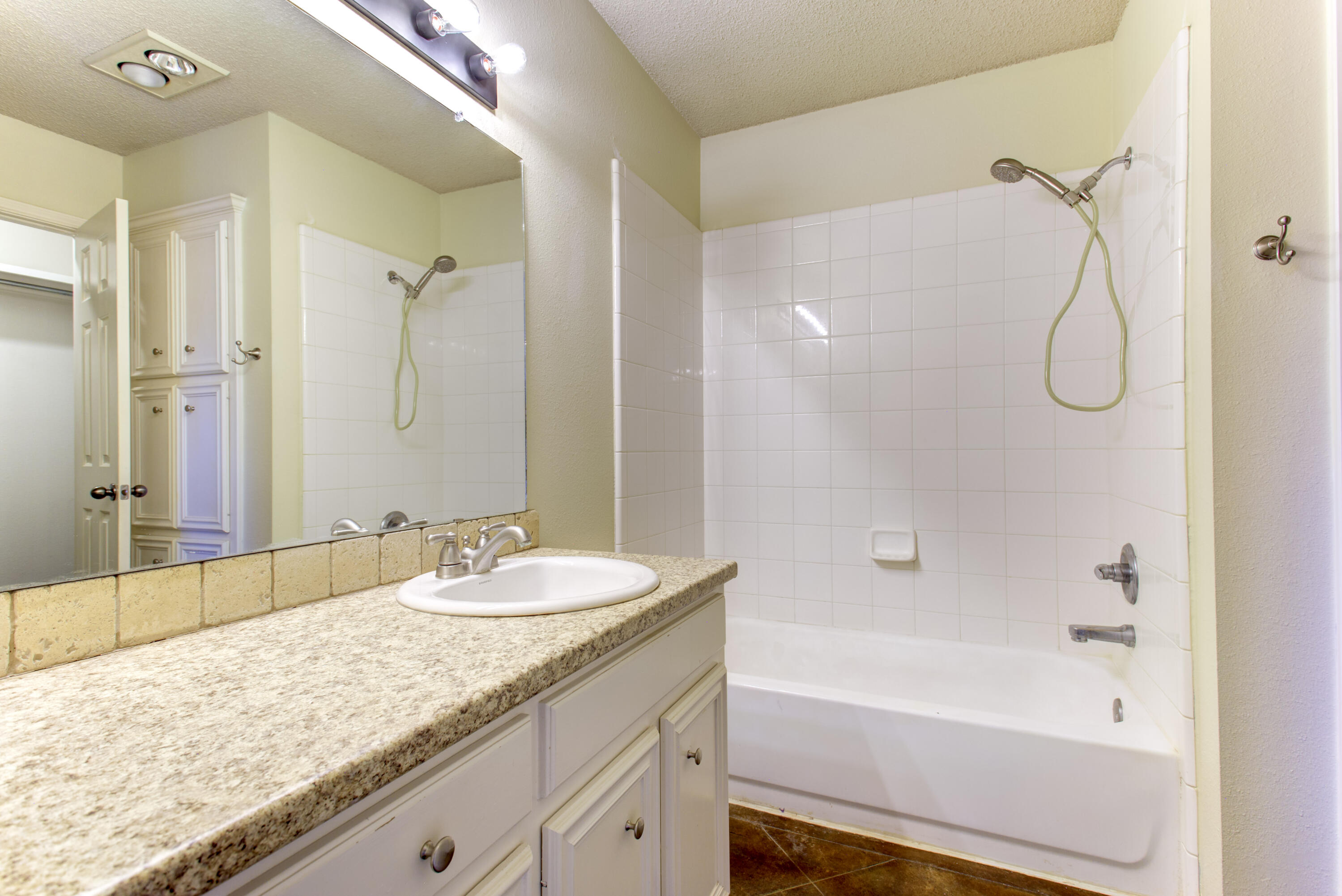 6804 7th Street Lubbock, TX 79416 - Photo 17 of 42 a bathroom with a granite countertop sink a mirror and a bath tub