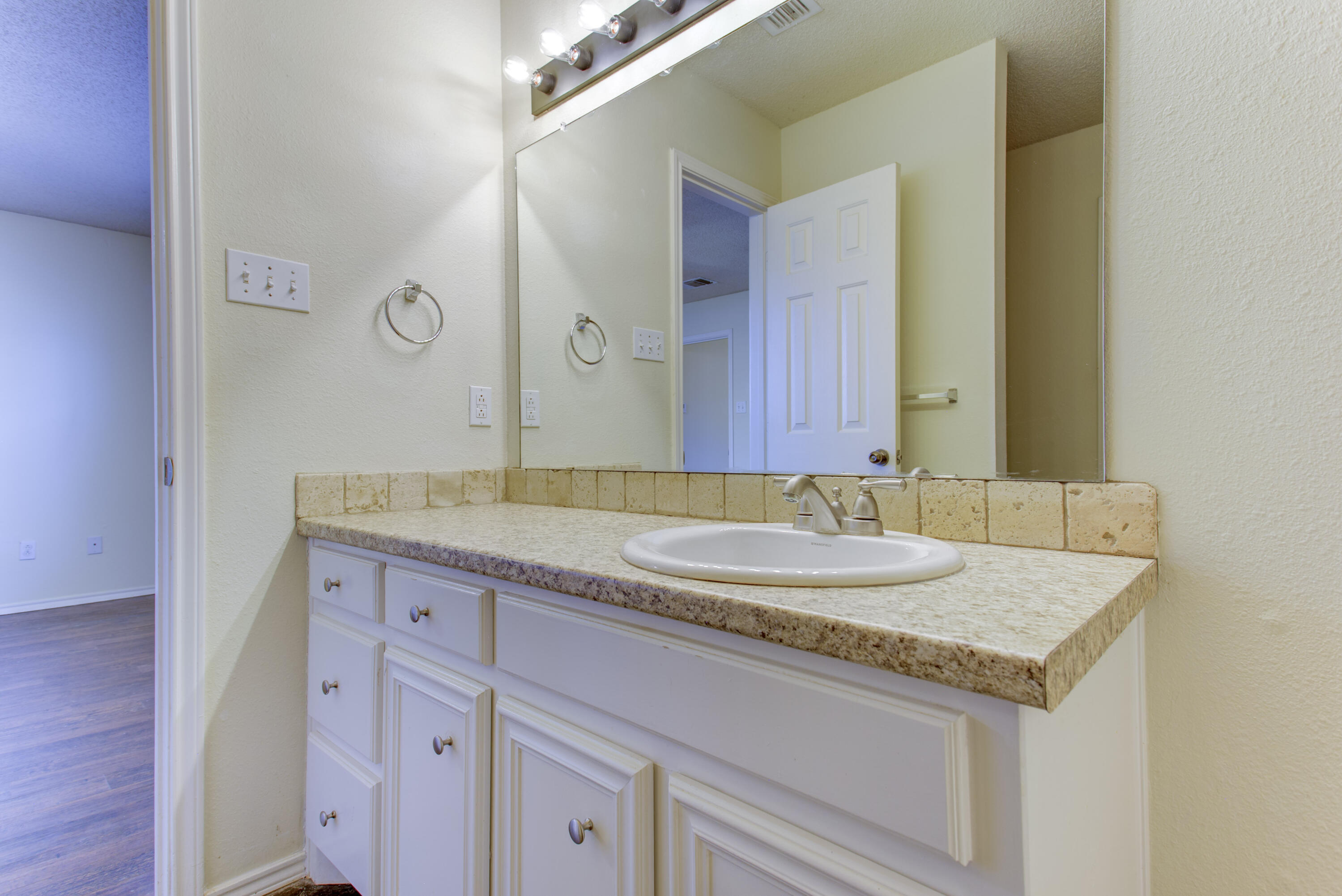 6804 7th Street Lubbock, TX 79416 - Photo 18 of 42 a bathroom with a granite countertop sink and a mirror